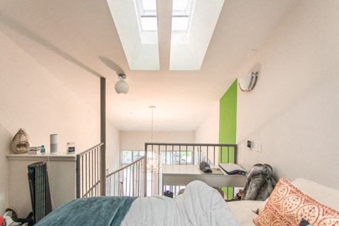 A bedroom with a bed, a couch, and a green accent wall.