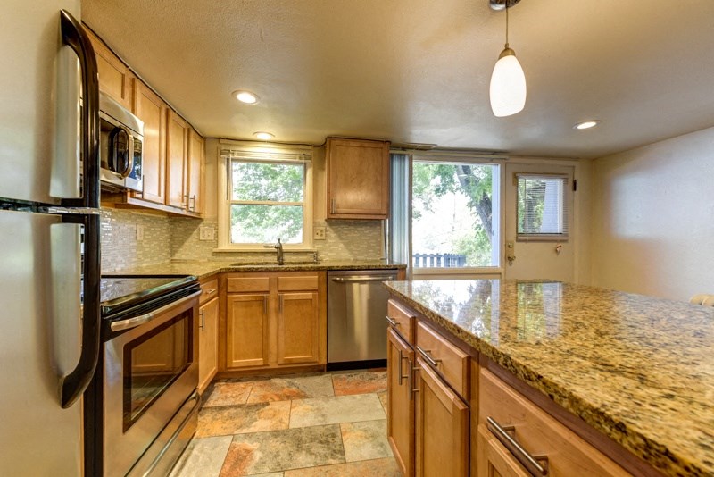 an updated kitchen with granite counter tops and wooden cabinets