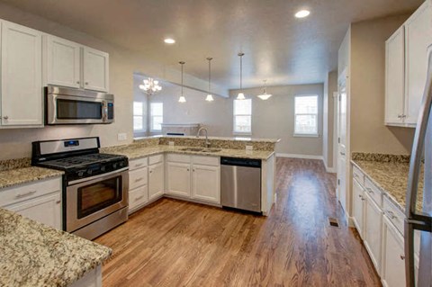 a large kitchen with white cabinets and a wooden floor