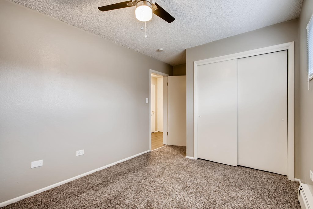 A room with a ceiling fan and carpeted floor.