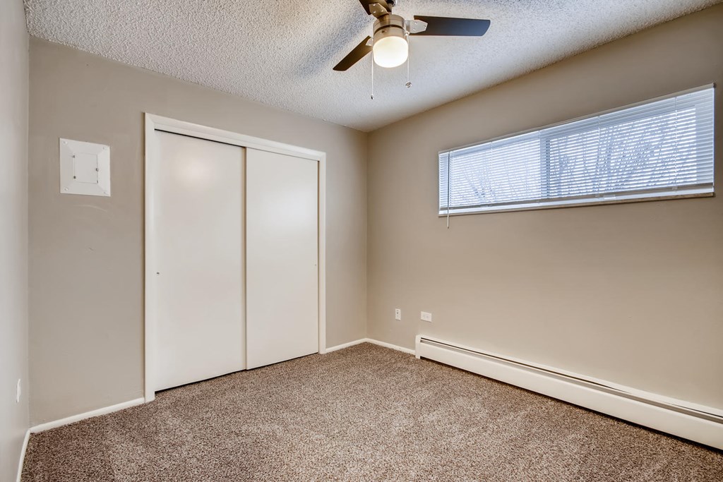 A room with a ceiling fan and a window with blinds.