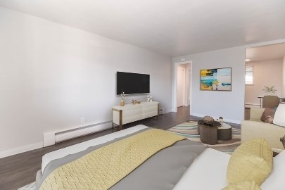 A living room with a white couch and a grey and yellow bedspread.