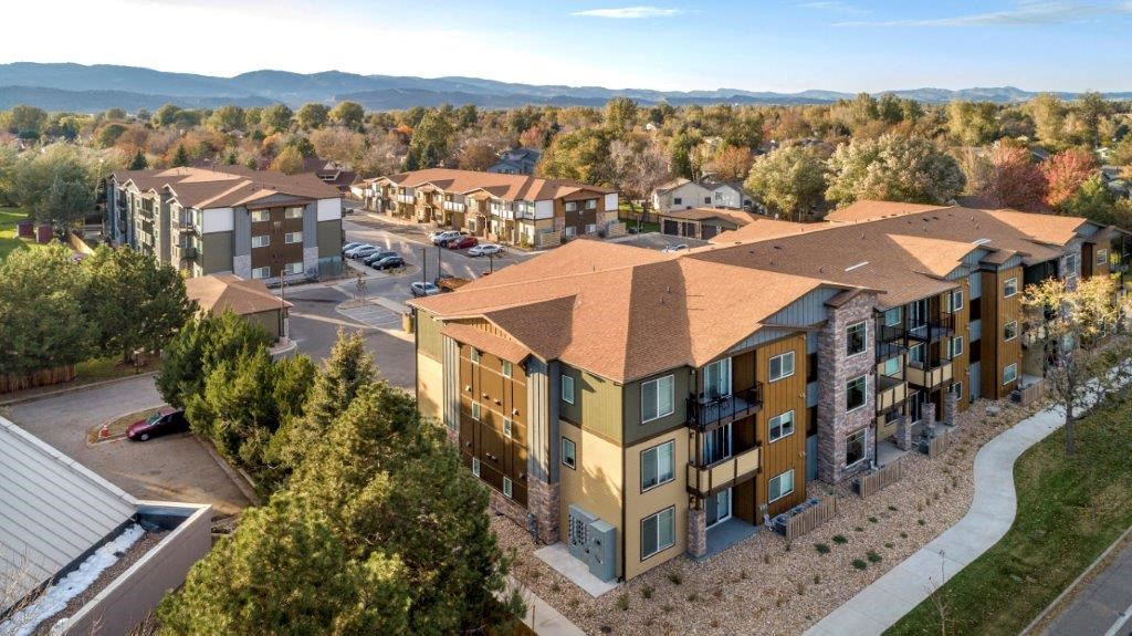 an aerial view of an apartment complex with trees and mountains in the background