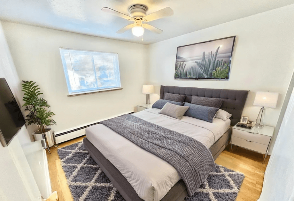 A bedroom with a bed, a ceiling fan, and a window.