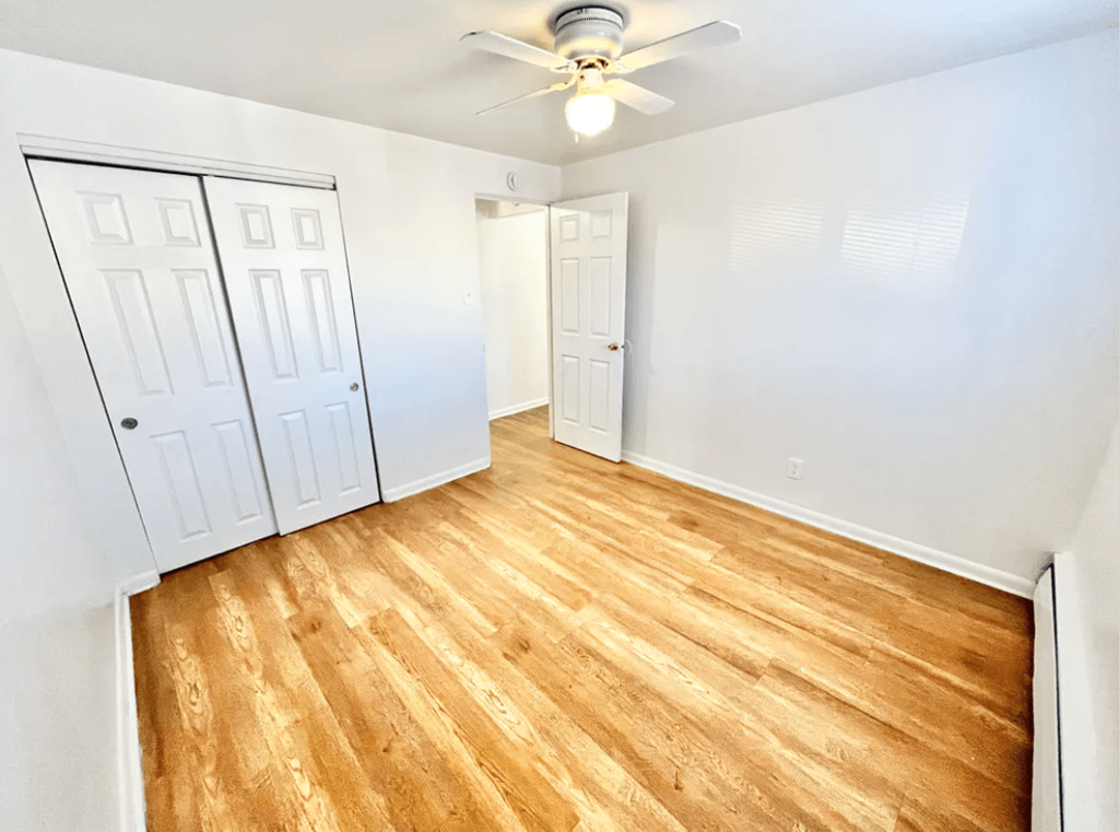 A room with wooden flooring and white walls.