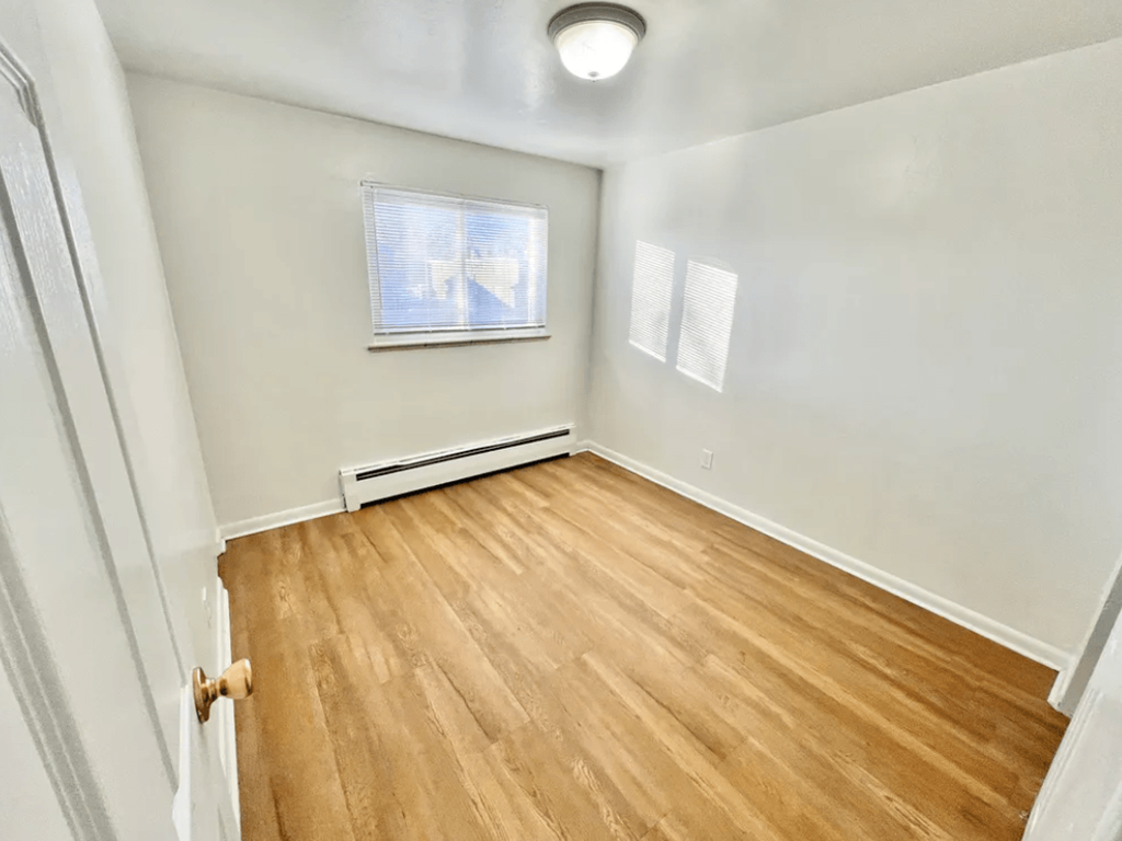 A room with wooden flooring and a window.