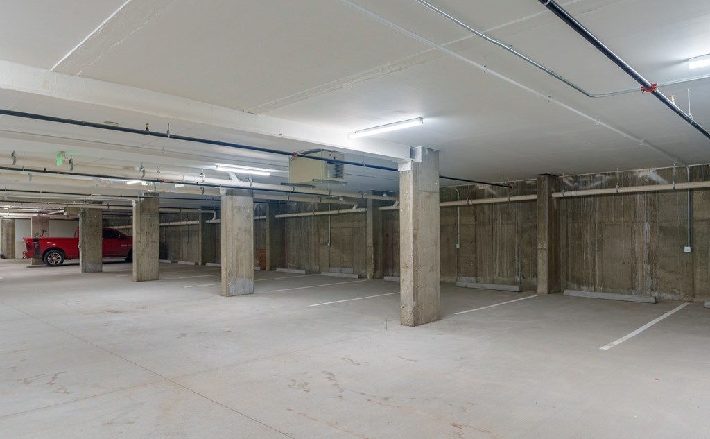A spacious, unfinished basement with concrete floors and walls, and exposed pipes and ducts.