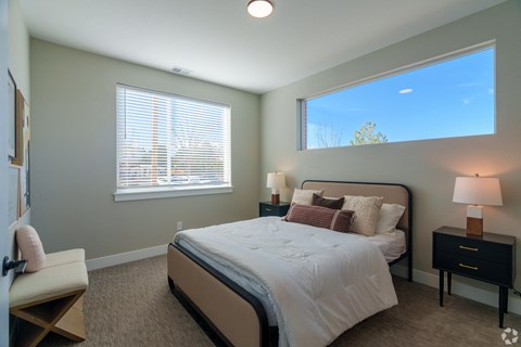 A bedroom with a large bed, a chair, and a window with blinds.
