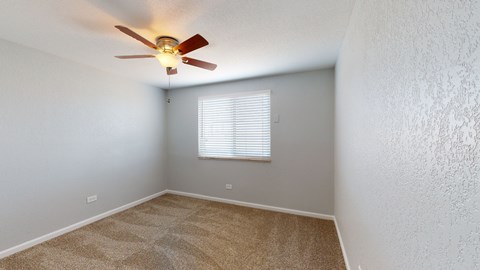 A room with a ceiling fan and carpeted floor.