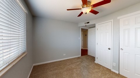 A room with a ceiling fan and carpeted floor.