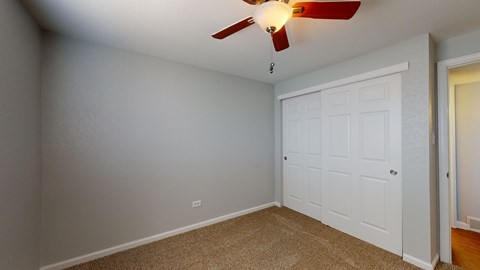 A room with a white door and a ceiling fan.