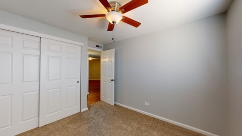A room with a ceiling fan and two doors.