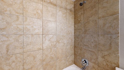 A bathroom with beige tiles and a white toilet.