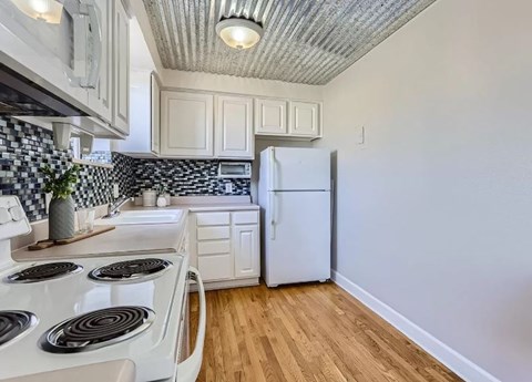 A kitchen with a white stove top and a white refrigerator.
