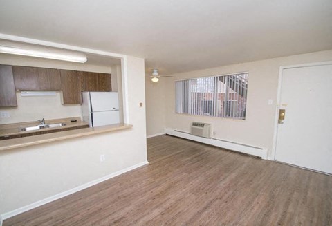 A kitchen with white appliances and wooden floors.