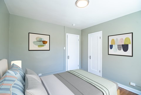 A bedroom with a bed and two framed pictures on the wall.