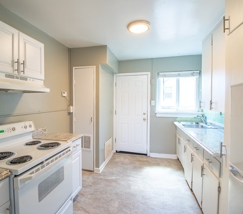 A kitchen with a white stove and cabinets.