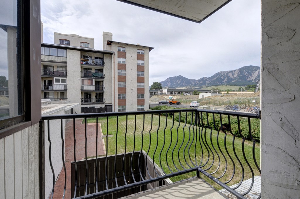 the view from the balcony of a apartment building with a park and mountains