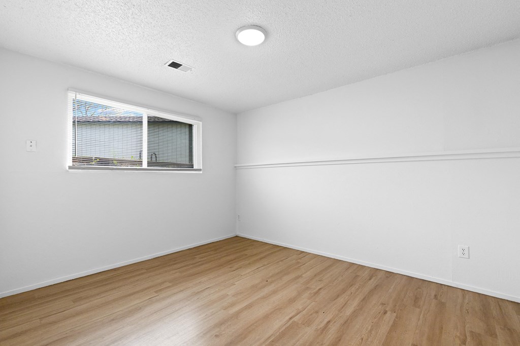 an empty room with wood floors and a window