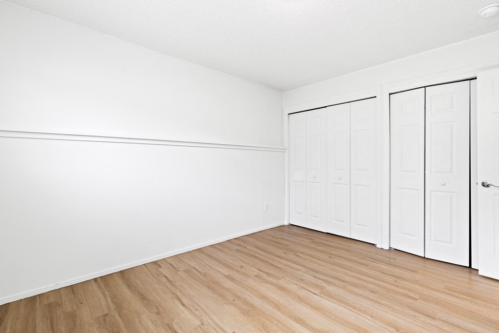 an empty room with white walls and wood floors