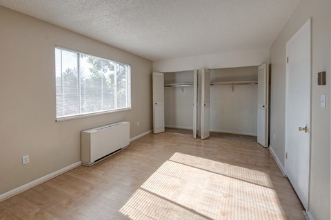 an empty living room with a large window and wood flooring