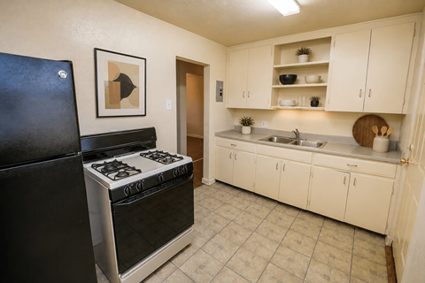 A black stove in a kitchen with white cabinets.