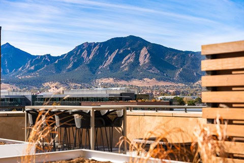 A mountain range is in the background of a building with a patio.