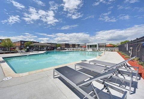 A pool with sun loungers and a building in the background.