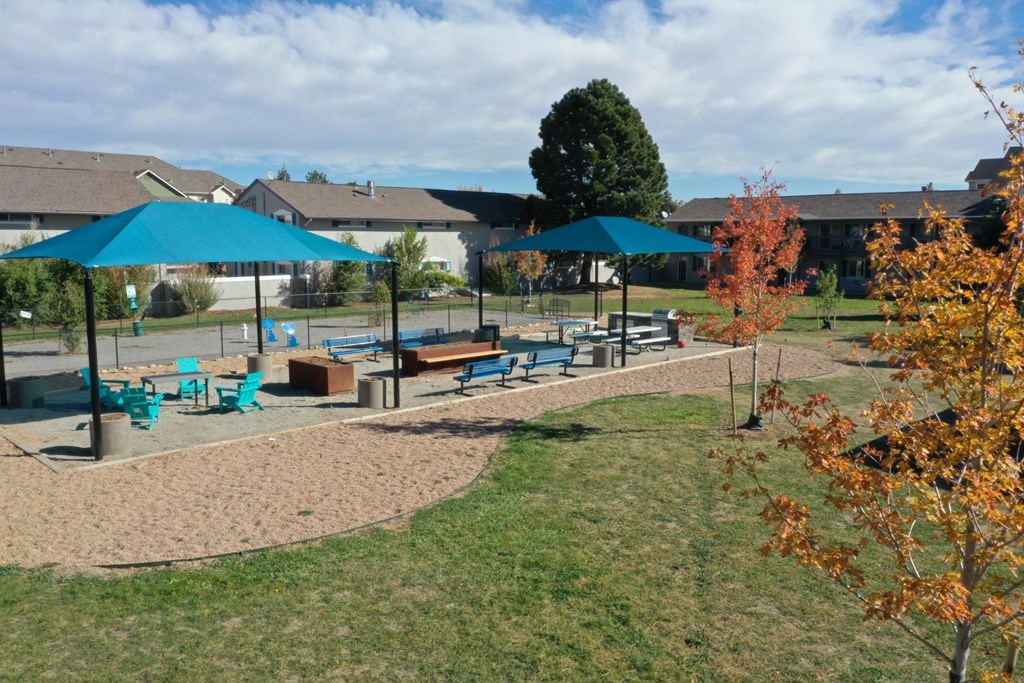 A playground with a blue umbrella and a slide.