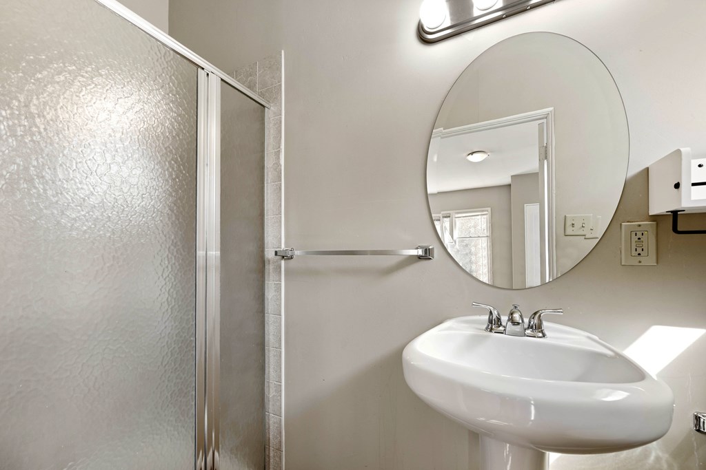 A bathroom with a white sink and a mirror.