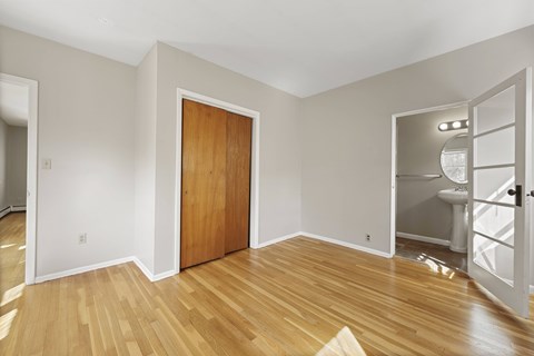 A room with a wooden door and a white door with a mirror on the other side.