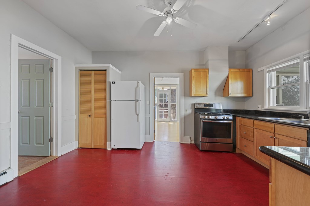 A kitchen with red flooring and wooden cabinets.