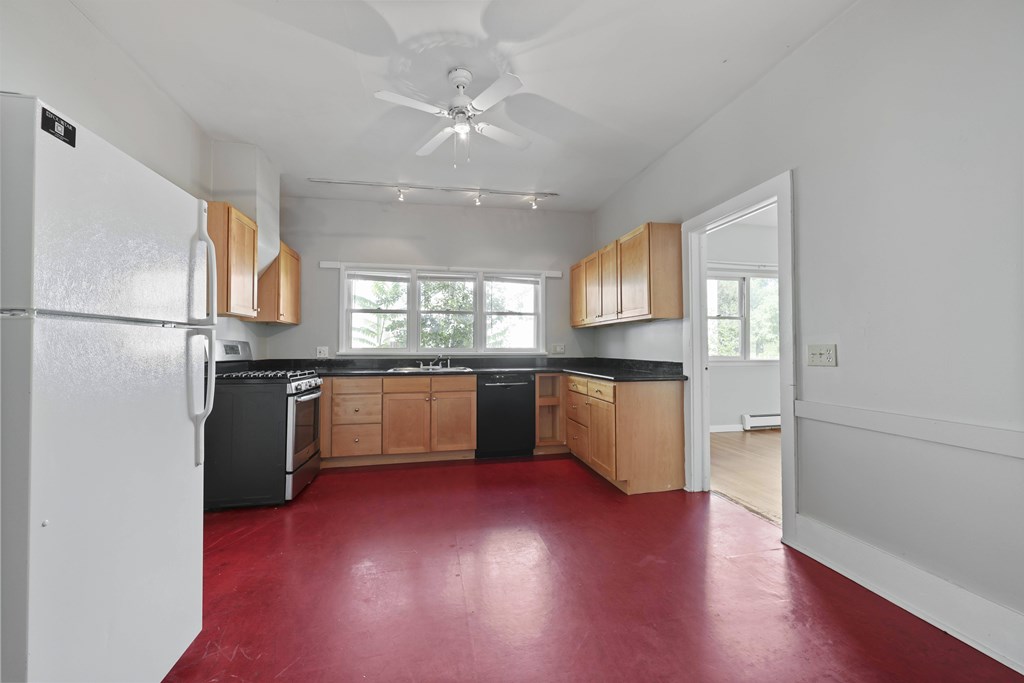 A kitchen with a white refrigerator and wooden cabinets.