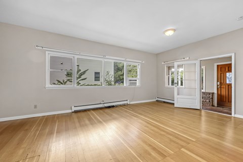 A room with wooden floors and a window overlooking a garden.