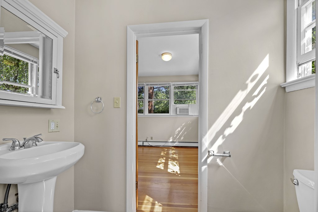 A white bathroom with a sink, mirror, and a door leading to a balcony.