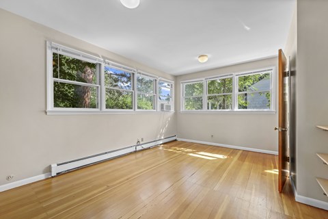 A room with wooden floors and three windows.