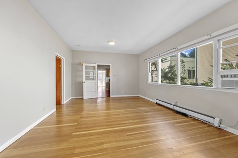 A room with wooden floors and a window with blinds.