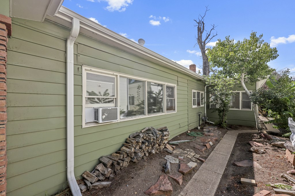 A green house with a stone wall and a tree in the background.
