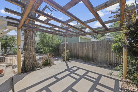 A wooden pergola over a patio with a concrete floor.