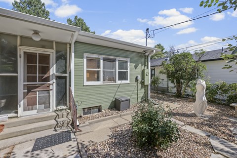 A green house with a white door and windows.