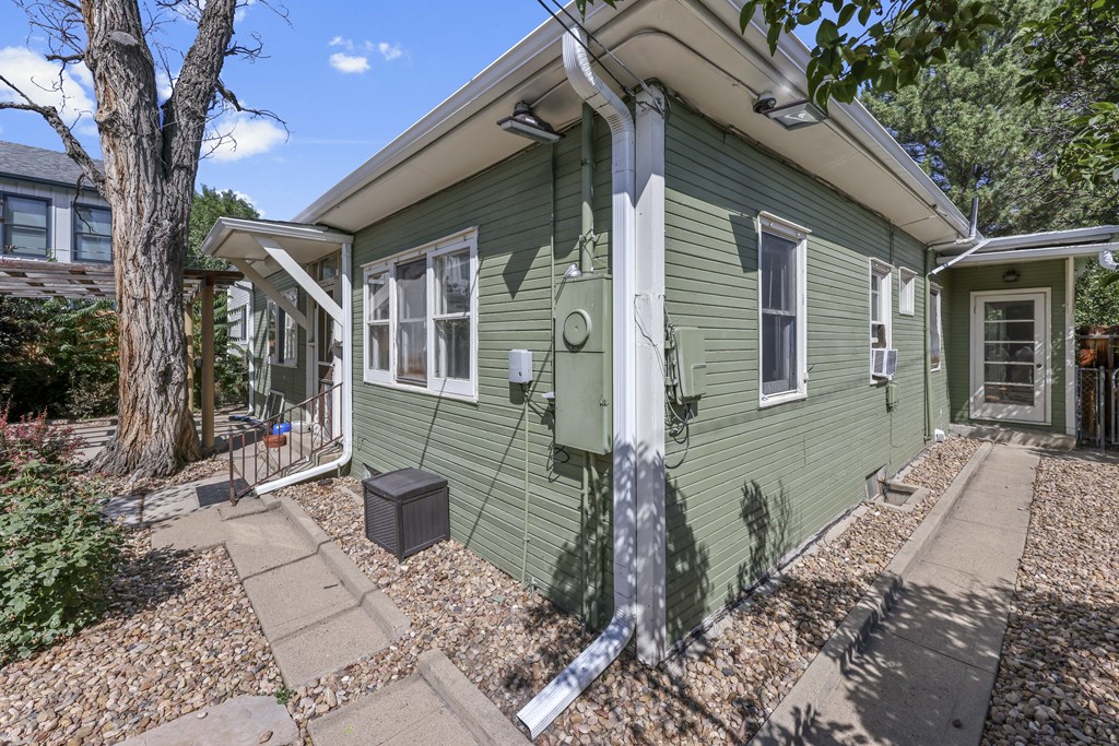 A green house with a white trim and a grey roof.