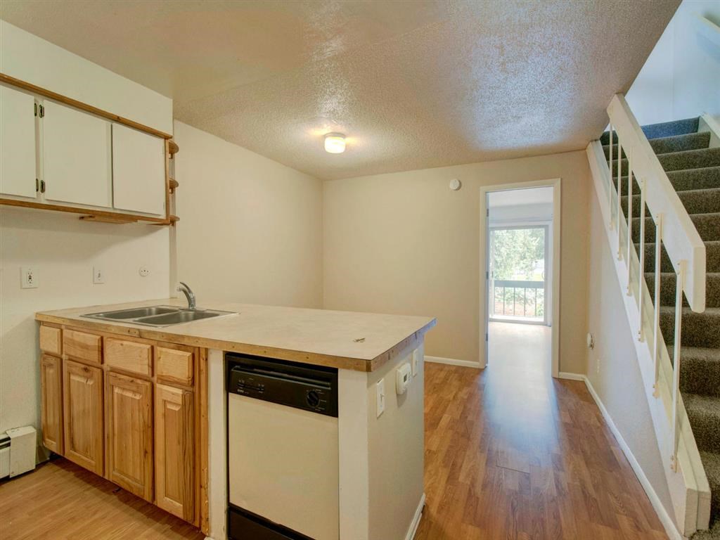 a kitchen with a sink and a dishwasher and a staircase