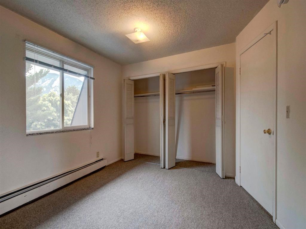 an empty bedroom with two closets and a window