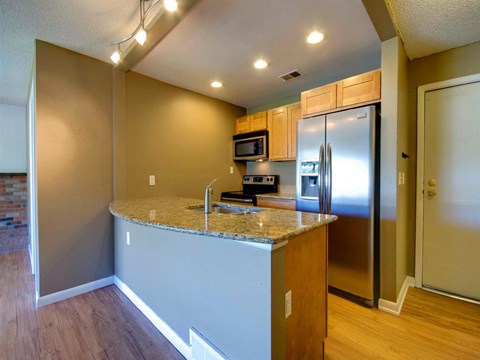 A kitchen with a granite countertop and stainless steel appliances.