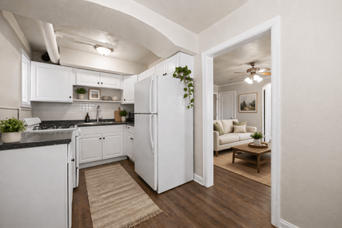 A kitchen with white cabinets and a black countertop with a rug on the floor.