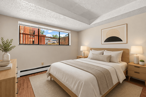 A bedroom with a large bed and a window overlooking a brick building.