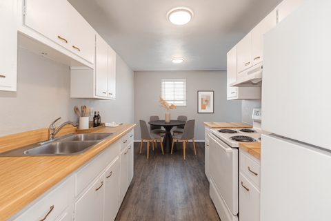 A kitchen with white cabinets and a wooden counter top.