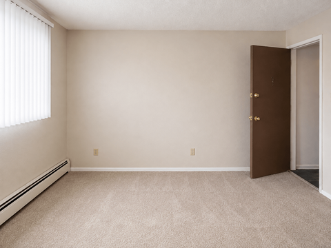 A room with a brown door and a window with blinds.