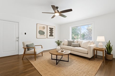 A living room with a white couch, a chair, a coffee table, and a ceiling fan.