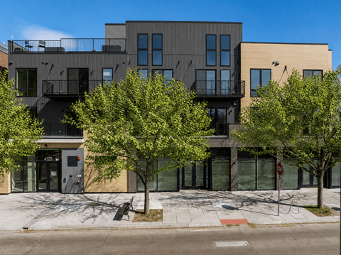 A modern building with a balcony and a tree in front of it.